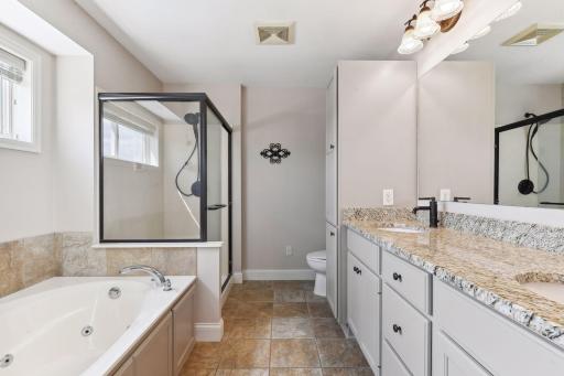 The Primary Bathroom features tiled floors, a comfort height vanity with two sinks and granite countertops, a jetted bathtub and separate shower.