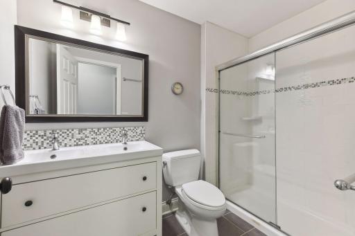 The 3/4 Hall Bathroom was remodeled with a furniture-style vanity featuring two sinks, a tiled shower with glass enclosure and updated fixtures.