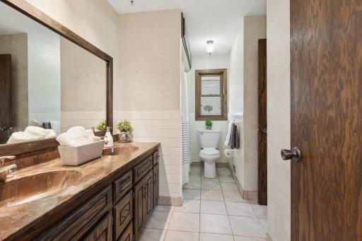 The bathroom features dual sinks, tile floors and a large mirror. Just outside the bathroom is a linen closet.