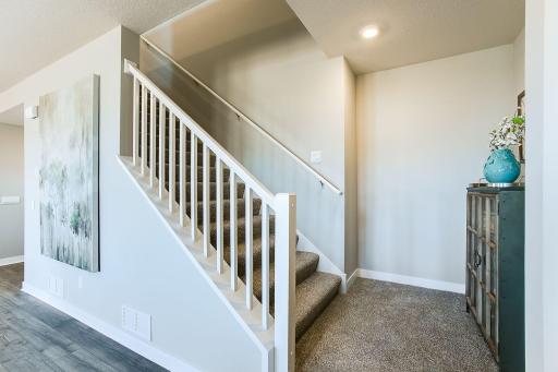 Our Jordan floorplan offer a nice wide staircase from the main level to the upper-level bedrooms and loft. Shown with open wooden railing and newel post.