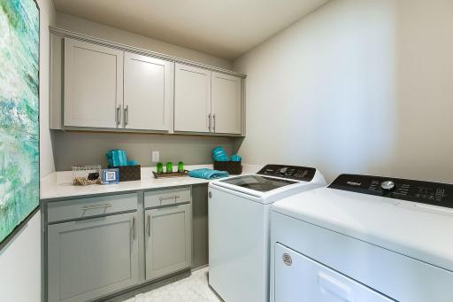 This laundry room boasts upgrade with cabinets and quartz counters making tasks a breeze!