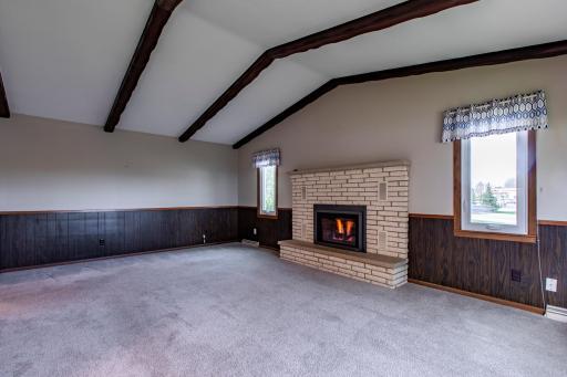 The living room boasts a lofty, beamed ceiling and a cozy fireplace, adding warmth and character to the space