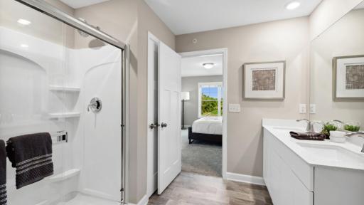 (Photo of a decorated model, actual homes finishes will vary) Dual sinks and a walk-in shower contribute to the spa-like atmosphere in the primary bathroom.