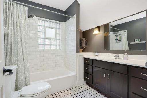 Full bathroom features classic black and white tile flooring, complemented by subway tile walls, offering a timeless and clean aesthetic.