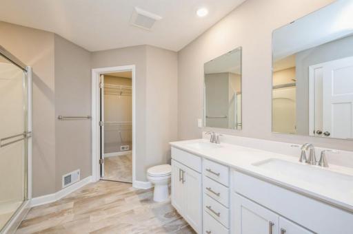(Photo of a similar home, actual homes finishes will vary) Dual sinks and a walk-in shower contribute to the spa-like atmosphere in the primary bathroom.