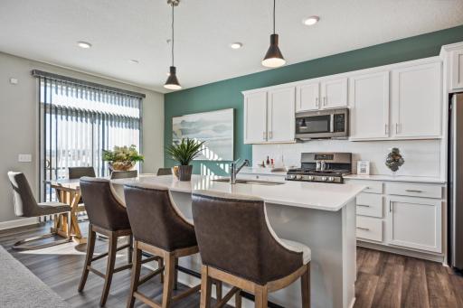 (Photo of a decorated model, actual homes finishes will vary) The spacious kitchen features a large center island, quartz countertops, LVP floors, stainless appliances and more!