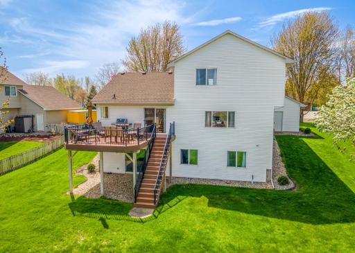 Capture the essence of outdoor entertaining with this aerial view showcasing a spacious backyard, complete with a charming elevated deck perfect for gatherings. The well-kept lawn with flowering trees.
