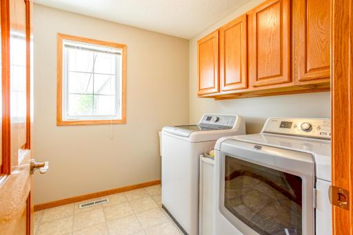 Efficiency meets style in this spacious laundry room equipped with high-end Maytag appliances set against rich wooden cabinetry, providing both functionality and aesthetic appeal.
