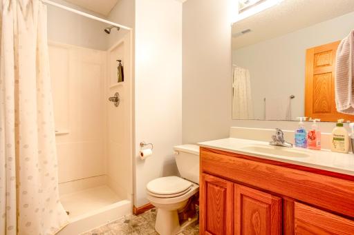 This clean and functional lower-level bathroom includes a full-size shower, ample vanity space, and well-organized toiletries, ensuring a practical and convenient space for daily routines.