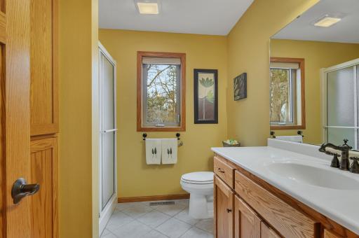 Main level three-quarter bathroom with a sit down shower, tiled flooring and custom vanity.