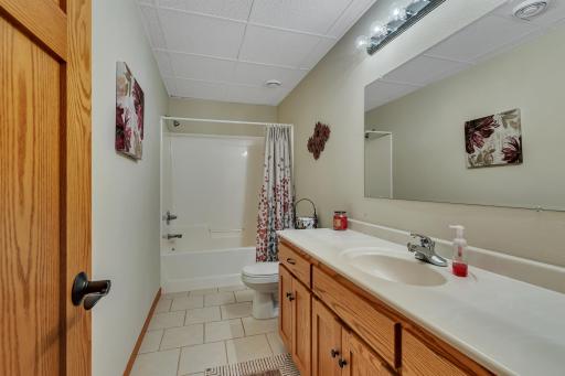 Lower level full bathroom with tiled flooring and custom vanity.