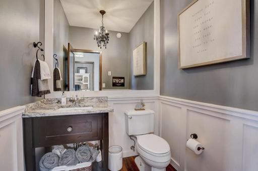 Lovely 1/2 bath off entryway with newer wainscotting, granite, light fixture and oversized mirror.