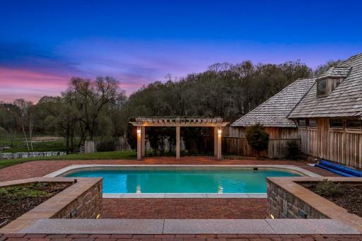 The in-ground pool is surrounded with paver patios and offers stunning views of the sprawling property.