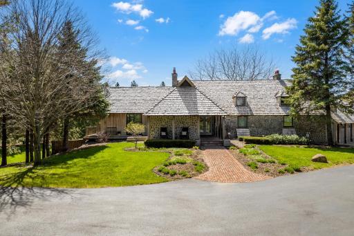 The home is surrounded by charming landscaping and paver patios.