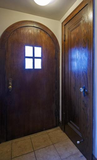 Arched wooden front door and coat closet. Ceramic tile floorings.