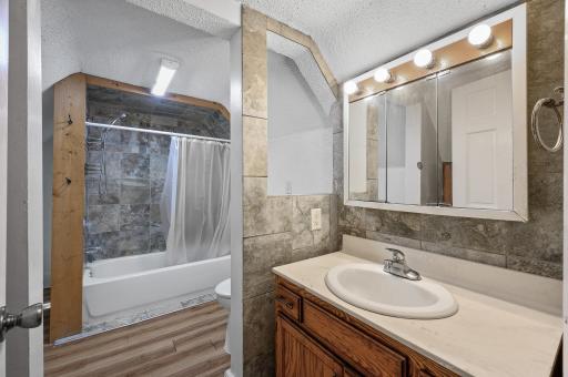 Upper level full bath with vinyl plank flooring and tile shower surround.