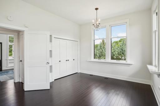 Large main floor bedroom features an extra deep closet, continued custom millwork and dual chandeliers.