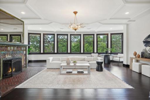 The main living room, with itâs bejeweled and glistening fireplace, overlooks the pool and entertaining deck through a wall of windows, bathing the room in natural afternoon light.
