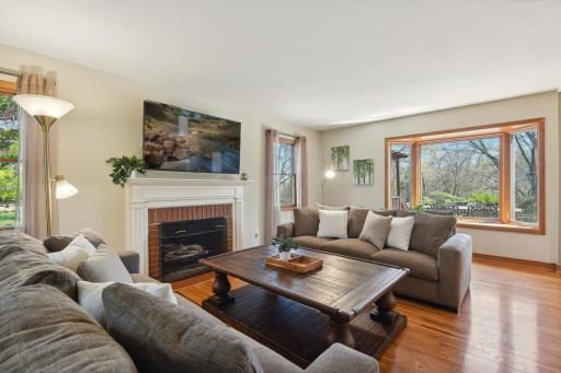 The living room showcases hardwood floors and a fireplace with brick surround