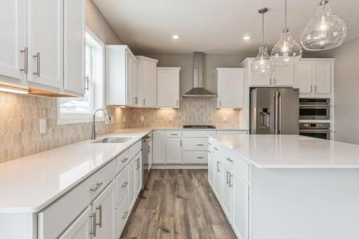 (Photo of a similar home, actual homes finishes will vary) Gourmet kitchen with huge island, walk in pantry and stainless appliances. This spacious gourmet kitchen features a walk-in pantry, quartz countertops, recessed lighting, LVP floors.