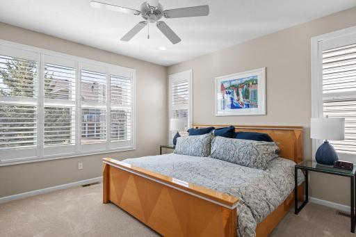 The main level also hosts the primary bedroom, providing a private sanctuary. Features include large backyard facing windows adorned with plantain shutters, ceiling fan, and plush carpet.