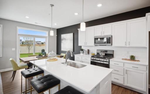 (Photo of decorated model, actual home's finishes will vary) This spacious kitchen features a large center island, quartz countertops, under mount sink, recessed lighting, LVP floors, stainless appliances and more.