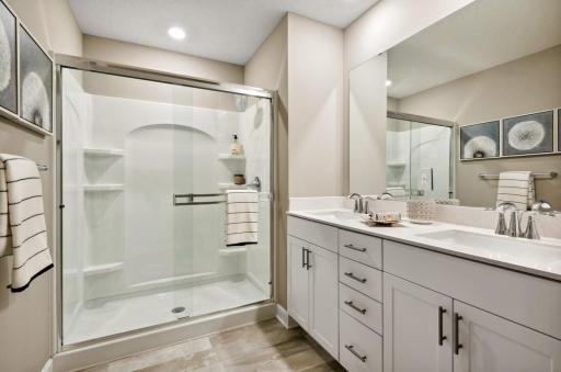 (Photo of decorated model, actual home's finishes will vary) An extension of the owner's suite, this private and spacious bath includes a double-vanity and shower.