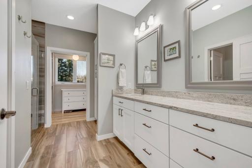 Luxurious private primary bathroom with huge custom vanity, full tiled shower, separate water closet, and access to huge closet and laundry. No cold feet getting out to the shower here - Tiled floors a heated!