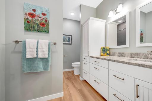 Lower Level Full bathroom boasts heated tile floors, custom cabinetry, solid surface vanity, and full tub/shower combination with tile surround.