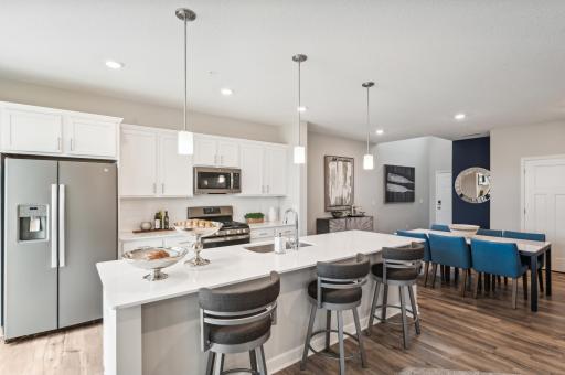 (Photo is of a model, actual homes finishes will vary) You will LOVE the extra large center island which is a show stopper as it not only offers a ton of counter space, it has beautiful quartz counter tops, dual trash pullout & ample storage.