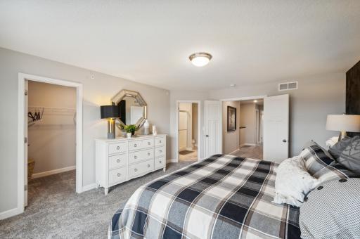 (Photo is of a decorated model, actual homes finishes will vary) The large primary bedroom welcomes you to relaxation & a place to catch a break. You will find a double door entrance, a large walk in closet and private ensuite bath.