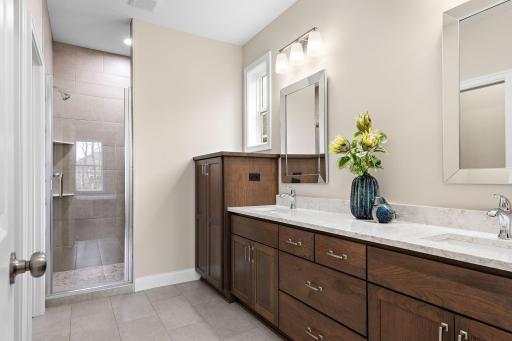 Owners bath with quartz vanity, heated flooring, built in linen & large shower