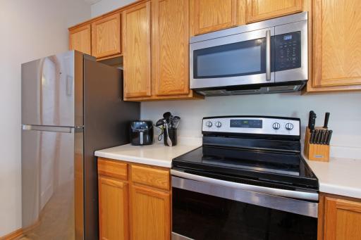 Stainless steel appliances and wood cabinets for storage. Electric stove with built-in microwave.
