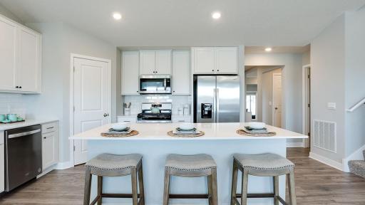 Gorgeous kitchen with large center island and nice pantry for storage. Stainless appliances, walk-in pantry, quartz counters, and subway backsplash! Photo of Model Home. Options and colors may vary. Ask Sales Agent for details.