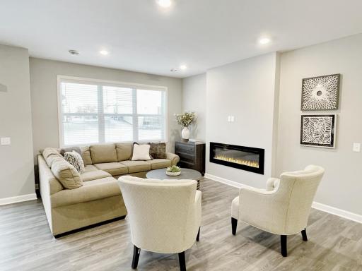 Photo of similar home, colors and finishes will vary. The home is covered in natural light and the hard surface flooring (LVP) is continued in the family room. The focal point of the family room is the centered electric fireplace.
