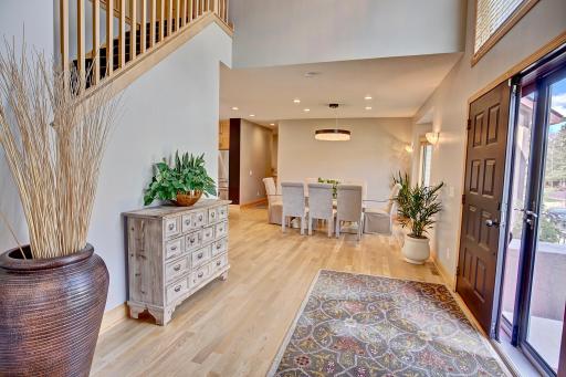 A stunning foyer with vaulted ceilings, a view of the open stairway leading upstairs and a visual tease of the custom dining and kitchen area that is sure to make every guest feel at home!