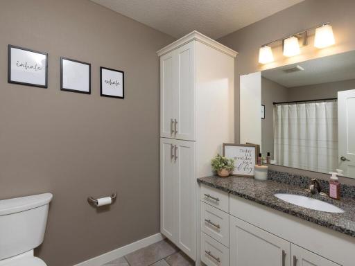 Upper level full bath with TONS of cabinet storage, tile flooring and natural stone countertops.