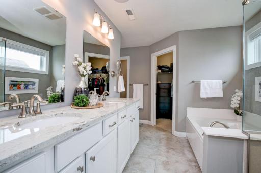 Warm, inviting spa-like primary suite with separate tub and shower, private commode and two walk-in closets.