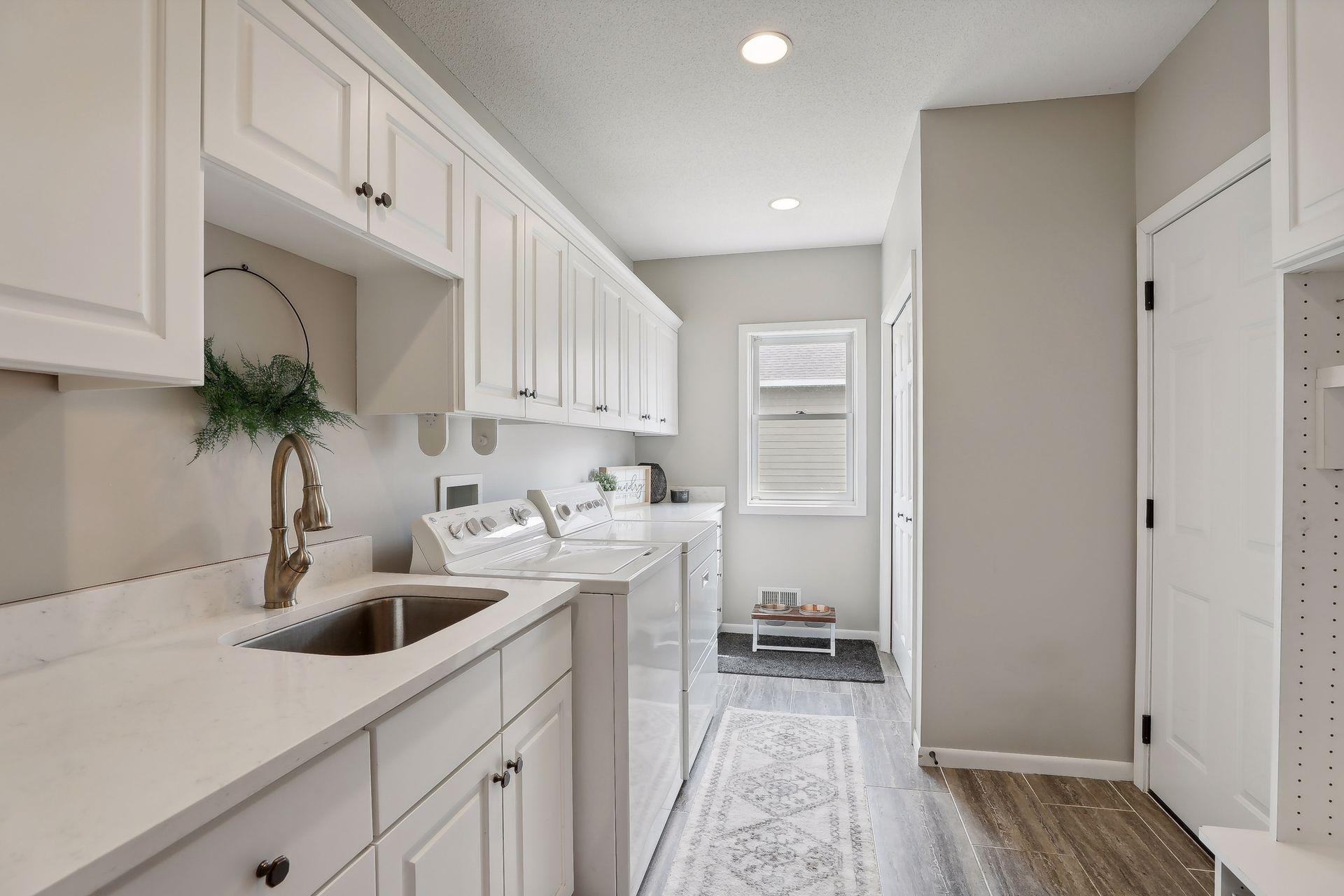 Two laundry spaces in this home. This laundry room / mudroom offers an abundance of cabinetry, closet and locker space on the main level. Modern white woodwork / trim creating an elegant mix of white and natural wood.