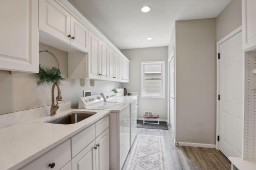 Two laundry spaces in this home. This laundry room / mudroom offers an abundance of cabinetry, closet and locker space on the main level. Modern white woodwork / trim creating an elegant mix of white and natural wood.