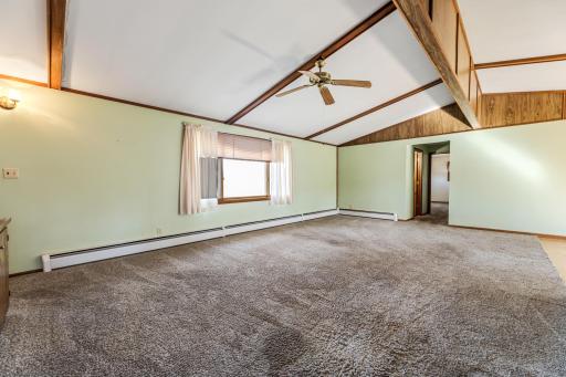 The living room features vaulted ceilings with wood accents, plush carpet and a ceiling fan for added comfort.