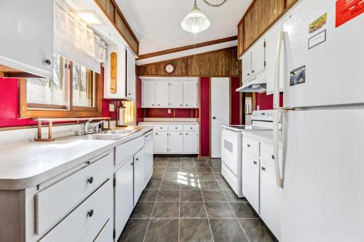 Galley kitchen with crisp white cabinets, tile floor and plenty of storage/prep space!