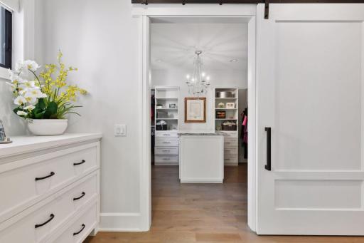The entry to the Primary Suite features a built-in dresser and linen cabinetry and a large custom barndoor leads into the dressing room.