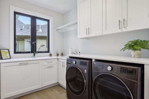 Conveniently located on the main level is the spacious Laundry Room which features a pull-out laundry hamper, laundry sink, quartz countertops and smart LG ThinQ steam washer and dryer.