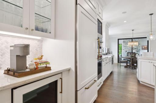 In addition to a large walk-in pantry, the Kitchen features a coffee and wine bar with a built-in beverage refrigerator and glass-front cabinetry.