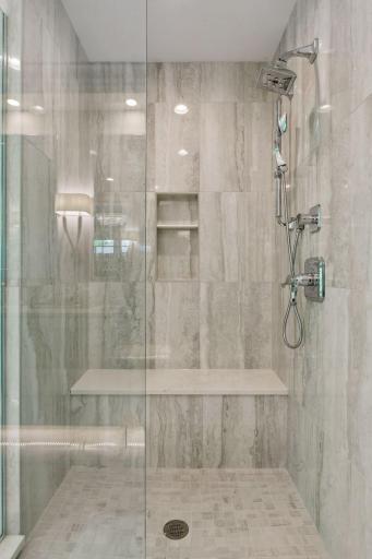 A tiled shower offers a built-in bench and glass enclosure.