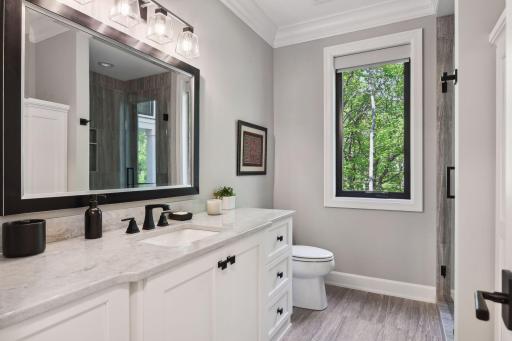 The Â¾ hall Bathroom offers a comfort-height vanity with quartz countertop, a large tiled shower and a wall of built-in linen cabinetry.