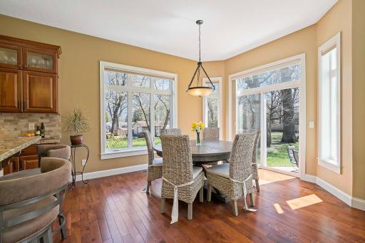 Flooded with natural light streaming in through the sliding glass doors, the dining space offers views of the outdoor surroundings. Adding warmth & charm to the space, the gleaming wood floors lend a touch of natural beauty to the combined space.