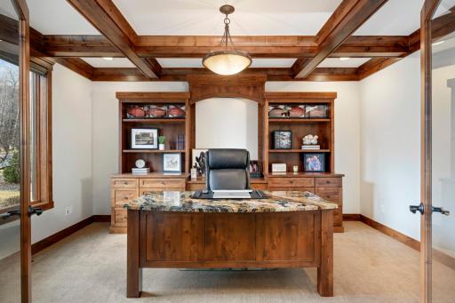 Home office features coffered ceiling and built-in bookshelves with storage below.
