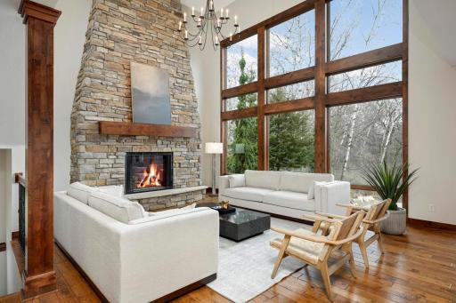 Living room boasts a two-story stone fireplace and floor-to-ceiling windows with an incredible view of the backyard.